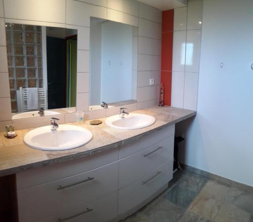 a bathroom with two sinks and a large mirror at Maison sous les arbres in Lit-et-Mixe