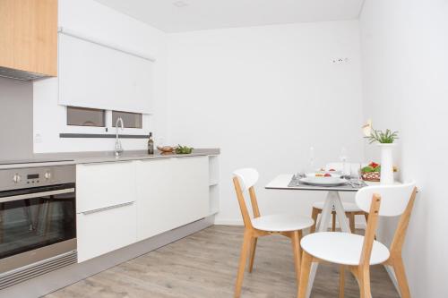 a kitchen with white cabinets and a table and chairs at The Marketplace by Storytellers in Funchal