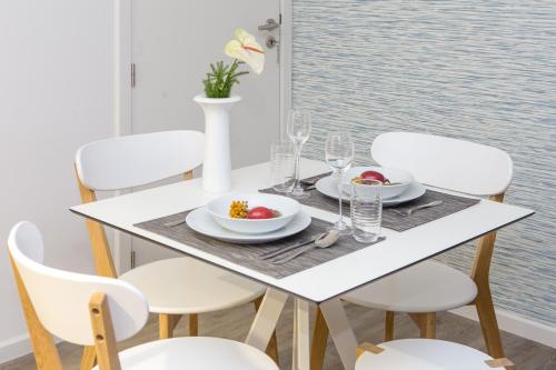 a white dining table and chairs with a bowl of fruit on it at The Marketplace by Storytellers in Funchal