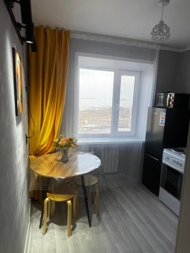 a small kitchen with a table and a yellow curtain at Квартира 1 линия in Balqash