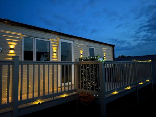 a house with lights on the deck at night at Bang Tidy 261 - Cabin - Wifi - Pool - Sleep 6 in Paignton