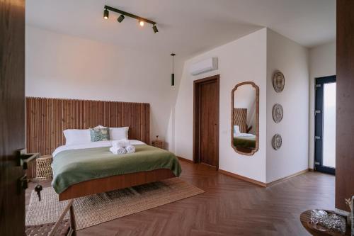 a bedroom with a large bed and a mirror at By The Lake - A Frame in Căciulaţi