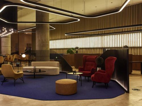 a lobby with chairs and tables and a waiting room at Pullman Lima San Isidro in Lima