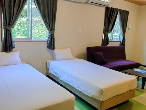 a bedroom with two beds and a chair and window at Rich Reson Ishigaki in Ishigaki Island