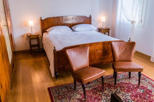 a bedroom with a bed with two chairs and two lamps at Agriturismo Dai Gobbi in Fara Vicentino