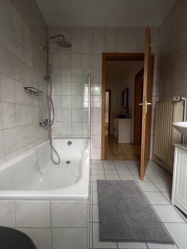 a white bathroom with a tub and a shower at Gemütlich unterm Dach in Baunatal