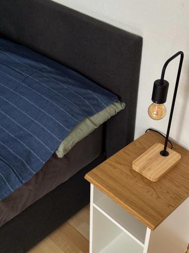 a bed with a night stand and a lamp on a table at Gemütlich unterm Dach in Baunatal