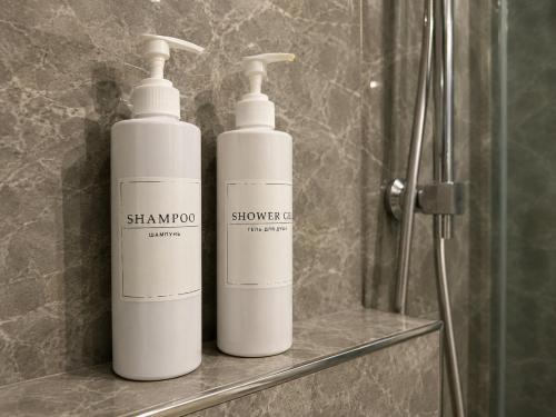 two white shampoo bottles sitting on a shelf in a bathroom at Nazarbayev avenue central studios in Almaty