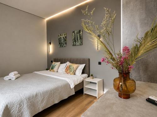 a bedroom with a bed and a vase with flowers at Nazarbayev avenue central studios in Almaty