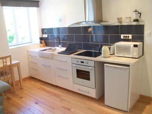 a kitchen with a stove and a sink and a microwave at Le Rosier in Segonzac