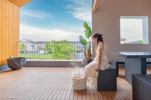a woman sitting on a bench in a room with a window at NAGASHIMA clas in Kuwana