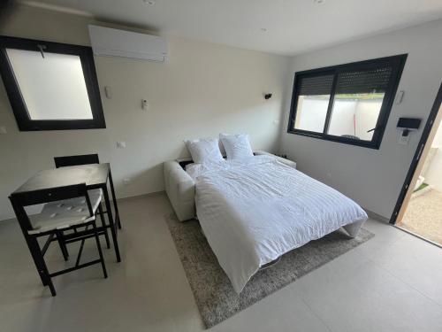 a white bedroom with a bed and a desk at Studio cosy avec terrasse in Montpellier