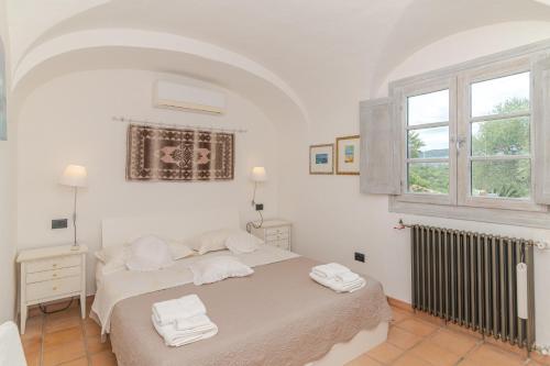 a white bedroom with a bed with towels on it at Villa Roccia d'oro piscina privata in Porto San Paolo