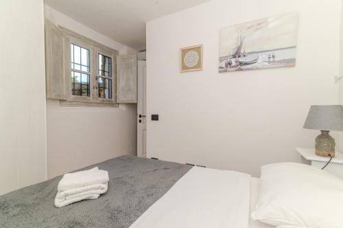 a white bedroom with a bed and a window at Villa Roccia d'oro piscina privata in Porto San Paolo