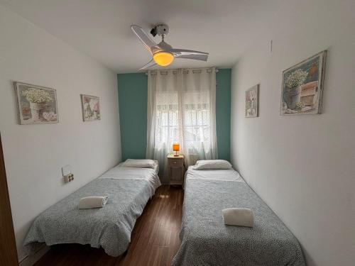 two beds in a room with a ceiling fan at Vilasardemarlux2 in Vilassar de Mar