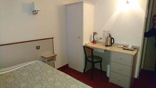 ein Hotelzimmer mit einem Bett, einem Schreibtisch und einem Bett in der Unterkunft Hôtel de France in Objat