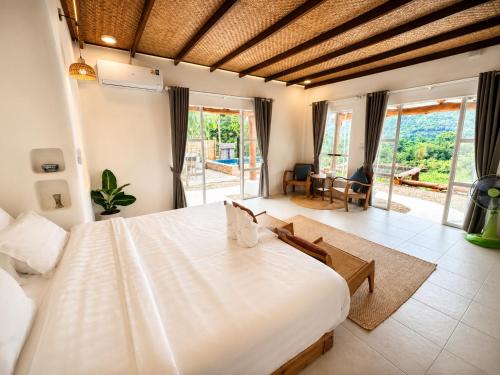 a bedroom with a large white bed in a room at Elephantpoolvilla maetang Chiangmai in Ban Muang Kut
