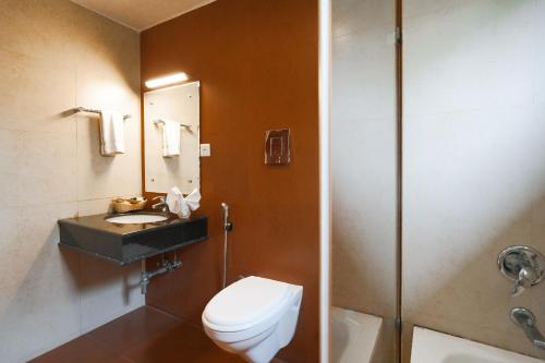 a bathroom with a toilet and a sink and a shower at Clay House in Trichūr