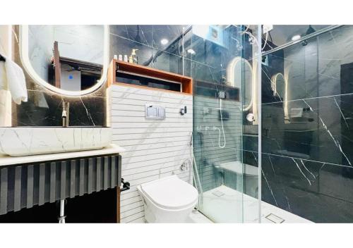 a bathroom with a toilet and a glass shower at Olive Serviced Apartments - Central Delhi in New Delhi
