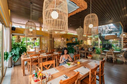 a woman sitting at a table in a restaurant at Chaykha Retreat Phuket in Chalong