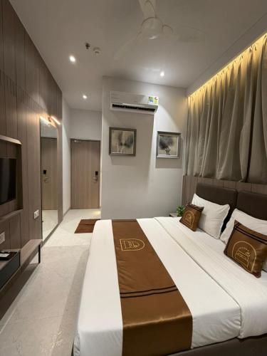 a bedroom with a large bed and a television at Hotel Unicorn Althan, Surat in Surat
