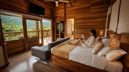 a woman sitting on a bed in a room with a view at LA RUSTICA MiNDO in Mindo