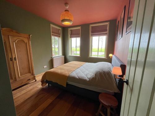 a bedroom with a bed and two windows at B&B huize Stoutenburght in Blesdijke
