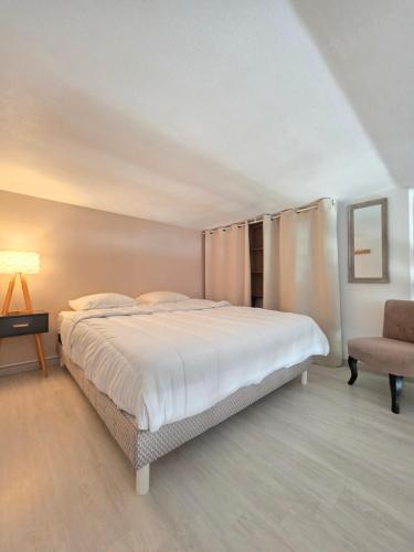 a bedroom with a large bed and a chair at Appart Bréti Plage 2 - duplex a 50m de la plage in Bretignolles-sur-Mer