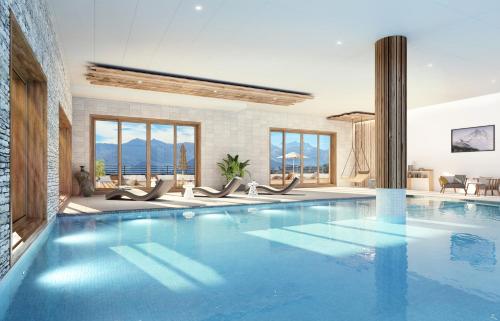 a large swimming pool with blue water in a house at TERRESENS Le Caprice Blanc in La Toussuire
