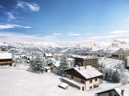 a town covered in snow with mountains in the background at TERRESENS Le Caprice Blanc in La Toussuire