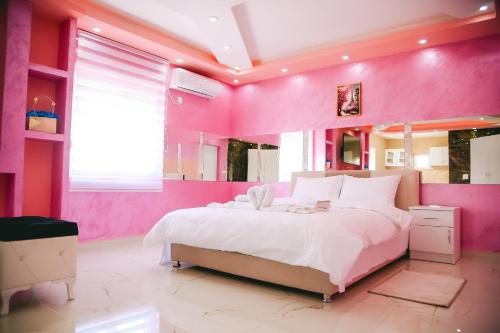 a pink bedroom with a large bed and a large mirror at LUX apartman savić in Aleksinac