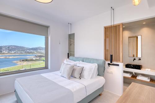 a bedroom with a bed and a large window at Panormos Bay Suites Luxury Resort in Mikonos