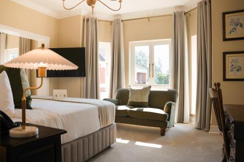 a bedroom with a bed and a chair and a lamp at Redlands Hotel in Pietermaritzburg