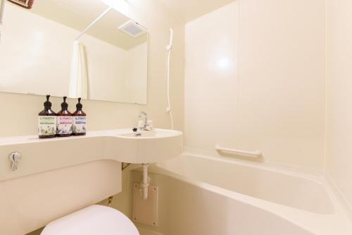 a bathroom with a sink and a toilet and a mirror at Rich Reson Ishigaki in Ishigaki Island