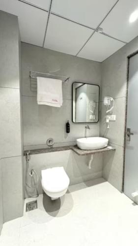 a bathroom with a toilet and a sink and a mirror at Hotel Unicorn Althan, Surat in Surat