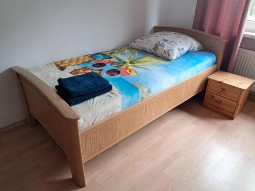 a small bed with a wooden frame and a table at Ferienwohnung Andy in Bremerhaven