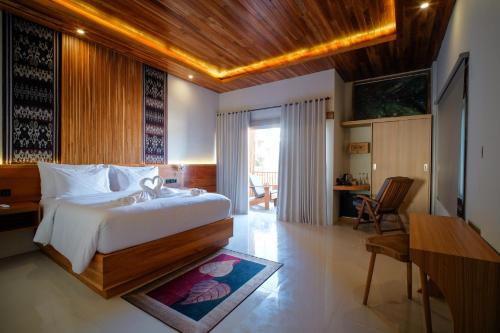 a bedroom with a bed and a table and a desk at Giri Rose Boutique Hotel in Kuta Lombok