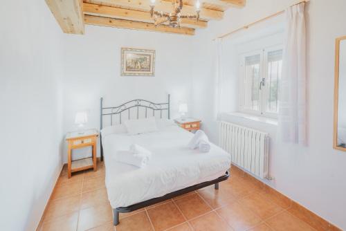 a white bedroom with a bed and a window at Casa Romo 1 in Chavida
