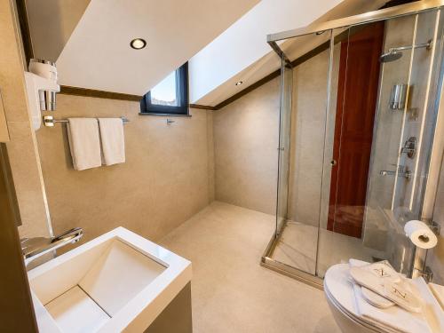 a bathroom with a glass shower and a sink at Nearest Airport Hotel in Arnavutköy