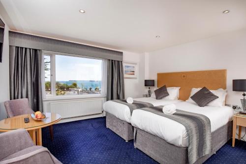 a hotel room with two beds and a window at Belgrave Sands Hotel & Spa in Torquay