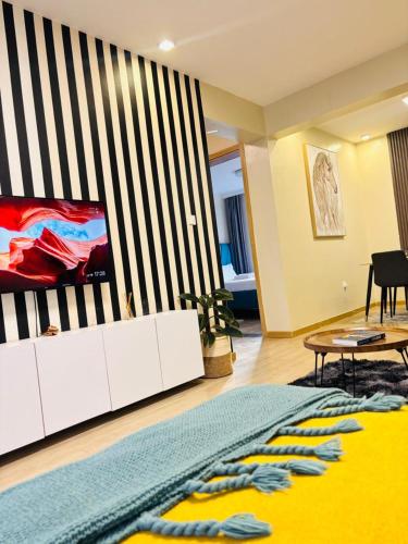 a living room with a tv on a wall at Two-Bedroom Apartment Near JKIA & SGR Free Parking & Wi-Fi By Irene in Nairobi