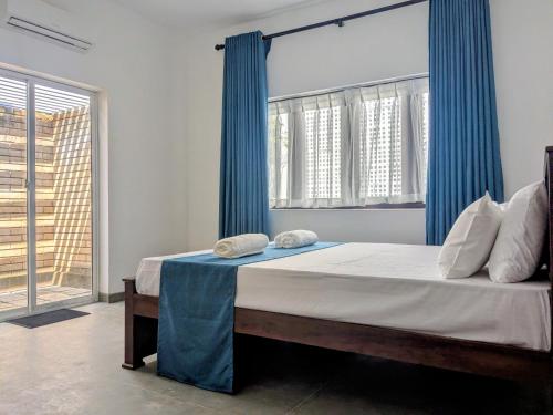 a bedroom with a large bed with blue curtains at Seth Villa Matara in Matara