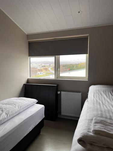 a bedroom with two beds and a large window at East Apartment in Egilsstaðir