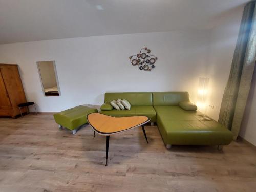 a living room with a green couch and a table at Ferienwohnung Gartenweg in Strullendorf