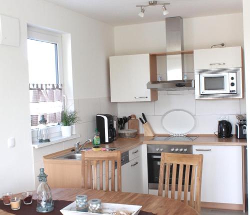 a kitchen with white cabinets and a table and a microwave at Jonas in Rerik