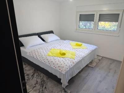 a bedroom with a bed with yellow towels on it at Apartman Florida ranč in Doboj