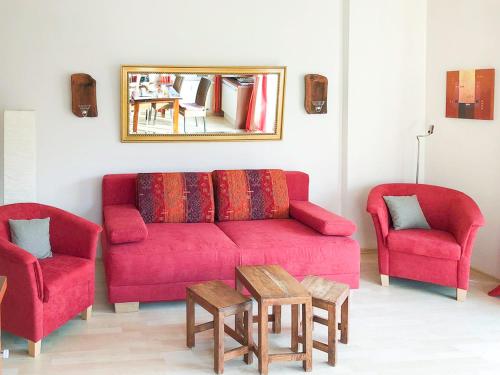 a living room with a red couch and two chairs at Ferienwohnung in der Villa Seestern in Nienhagen