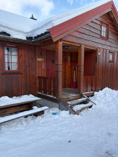 a wooden cabin with snow on the porch at Bakkestølveien 360 in Hol