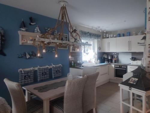 a kitchen with a table and chairs and a blue wall at Fischers Fritze in Fehmarn
