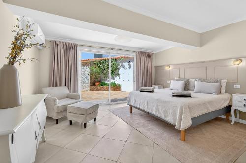 a bedroom with a king sized bed and a chair at Spacious Villa Victoria Heated Pool in Callao Salvaje